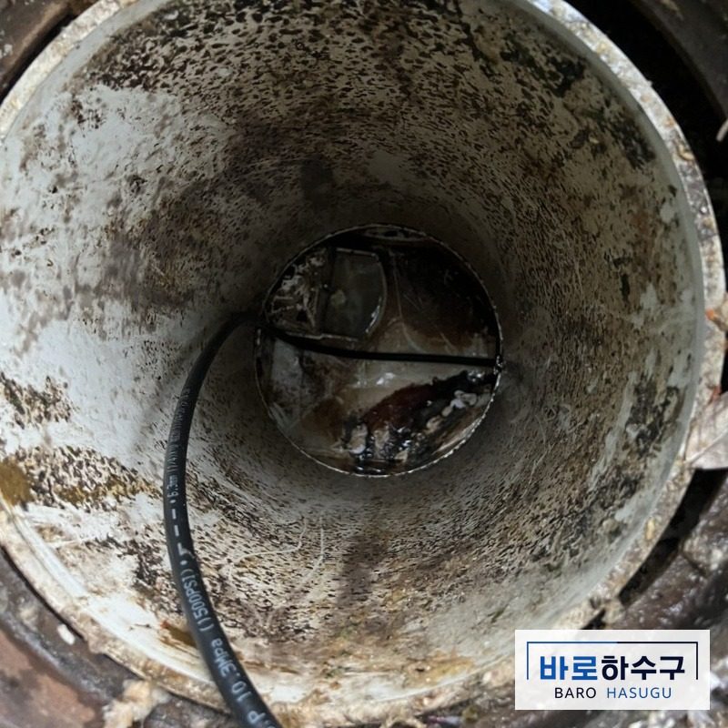 용인 수지구 오수받이 안쪽 배관에 세척 호스를 넣어 막힌 곳을 뚫는 작업 중 모습